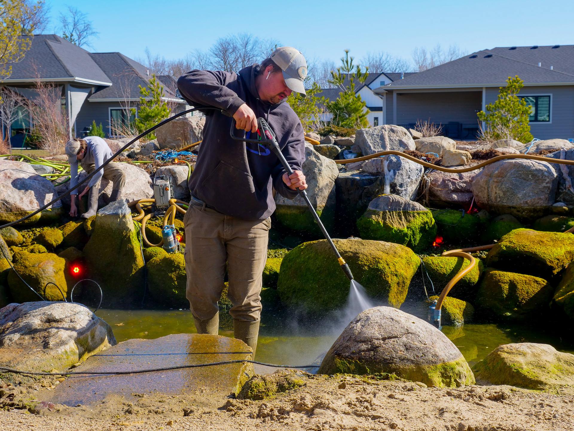 Crew draining and cleaning a garden pond during a spring service visit
