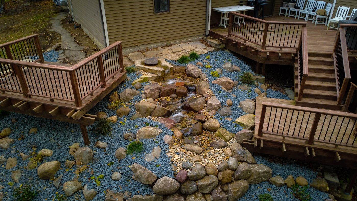 Aerial view of a pondless waterfall winding between two backyard decks