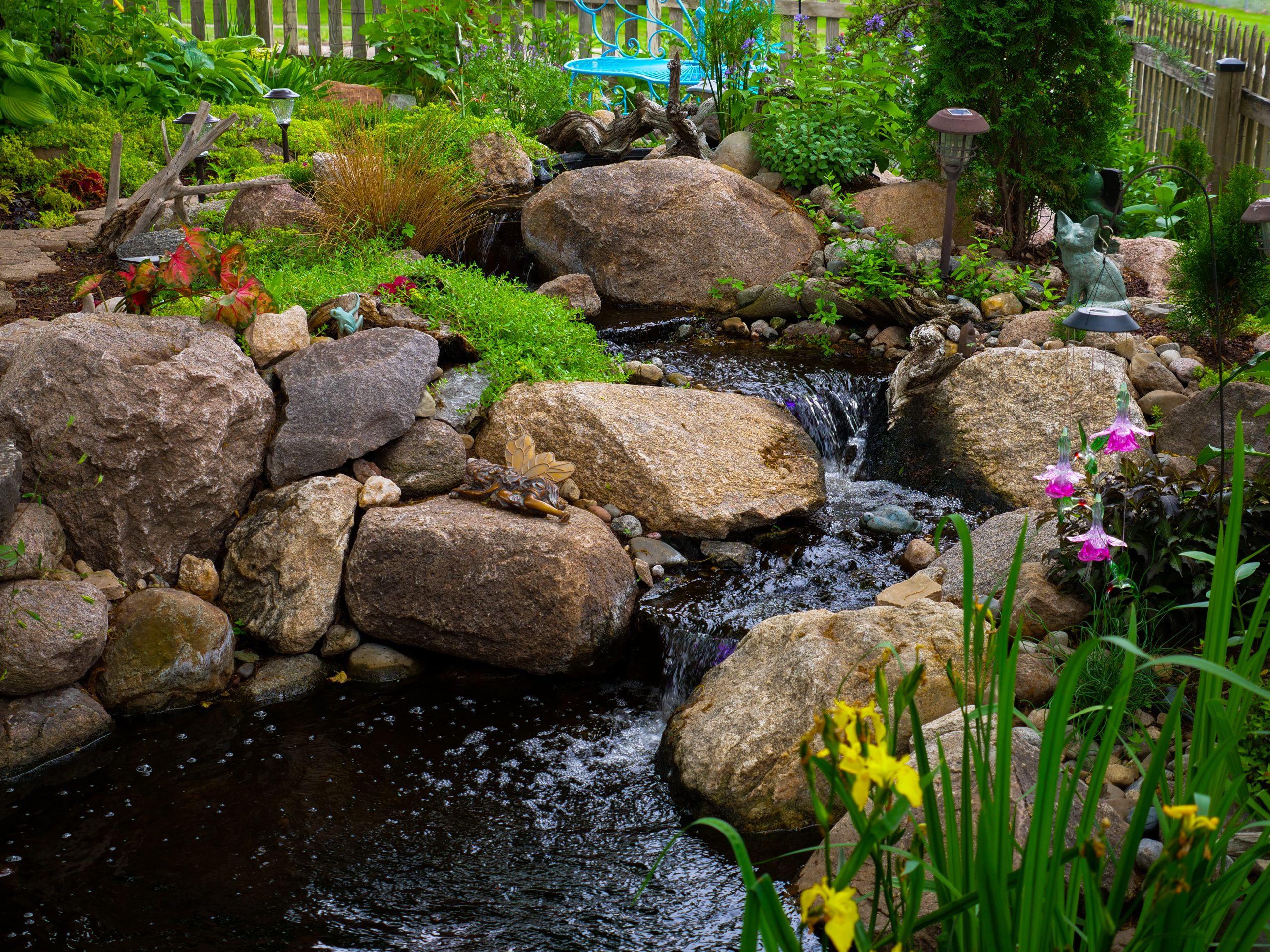 Rocky stream and waterfall with yellow iris in an Ankeny garden pond
