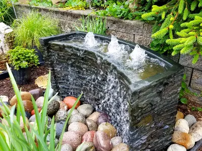 Pondless waterfall and fountain feature in a landscaped yard