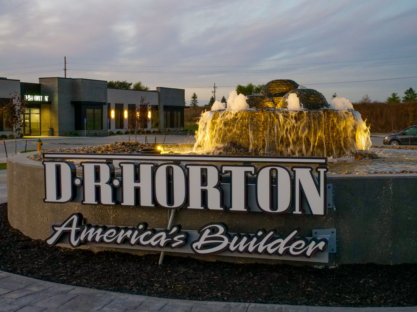 Illuminated commercial entry fountain bubbling over stacked slate at dusk