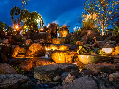 Large lit fountainscape with urns, bowls, and waterfalls at dusk