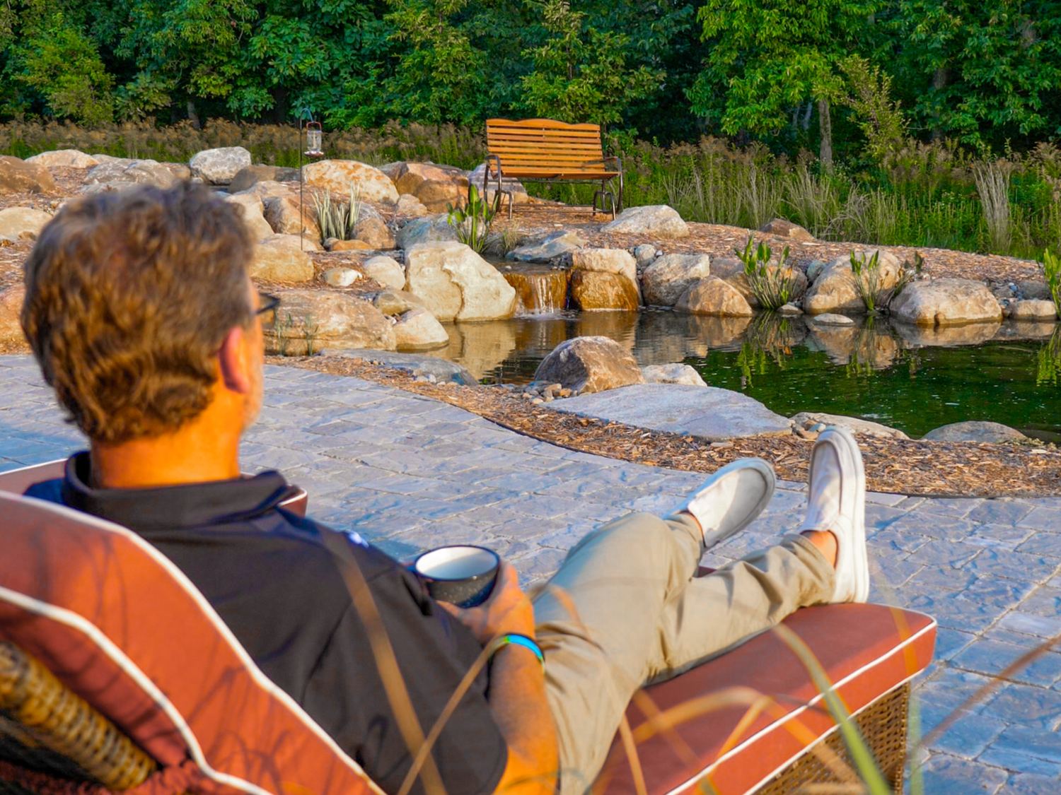 Backyard pond with a waterfall next to a cedar pergola with patio seating