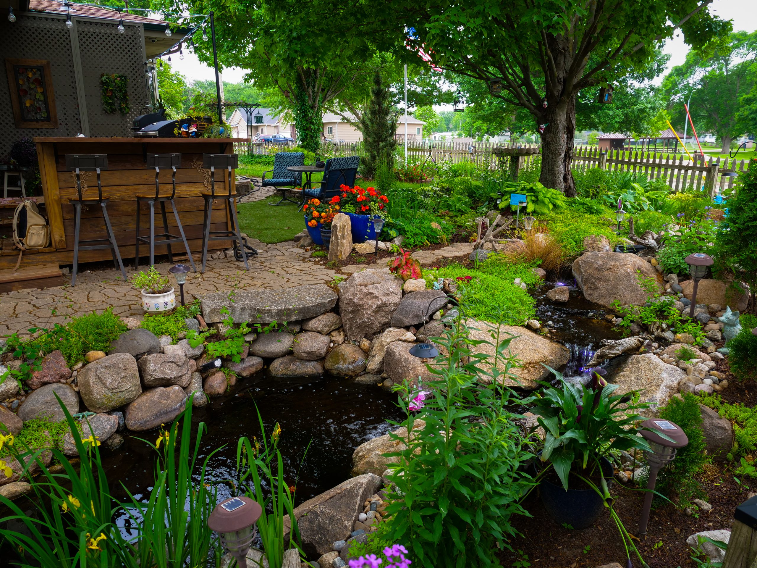 Ankeny garden pond surrounded by plantings with a backyard bar and patio