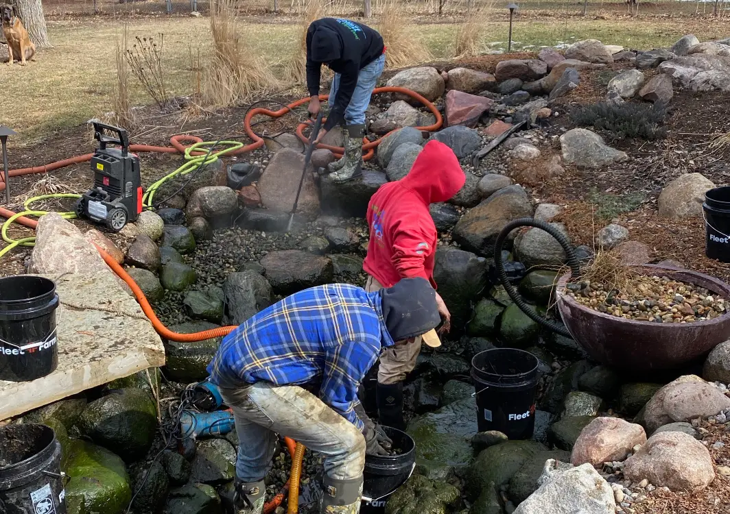 Just Add Water crew working inside a drained pond with hoses and buckets