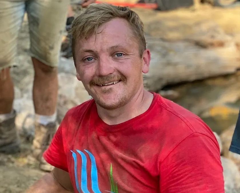 Smiling person outdoors in a red shirt.