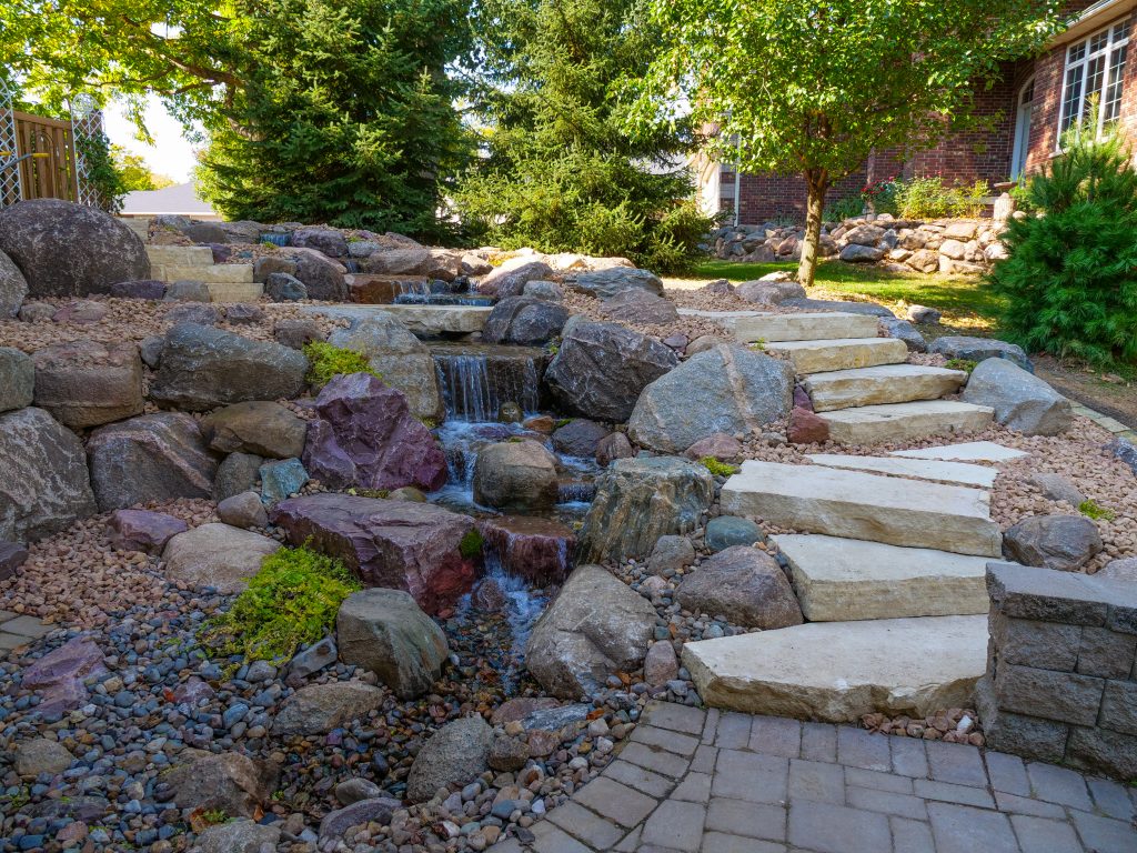 Stone path with water feature in garden landscape.